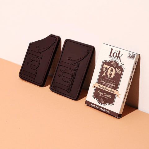 Two dark chocolate bars and their packaging on a peach background
